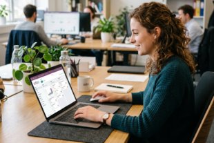 Woman using project management software on laptop in office.